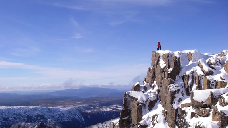 man on top of a snowy cliff