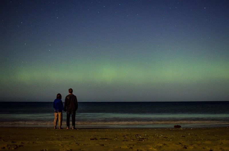 couple watching southern lights on a beach