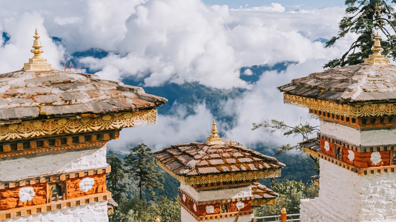 a view of a monastery in bhutan with the mountain clouds below