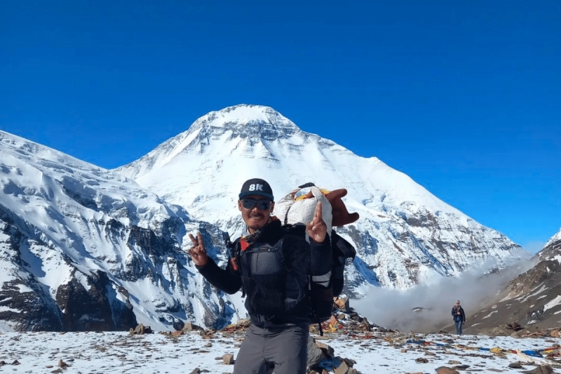 shanu sherpa posing in front of mountain