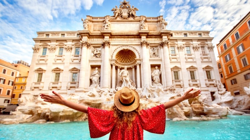 a woman in front of the trevi fountain