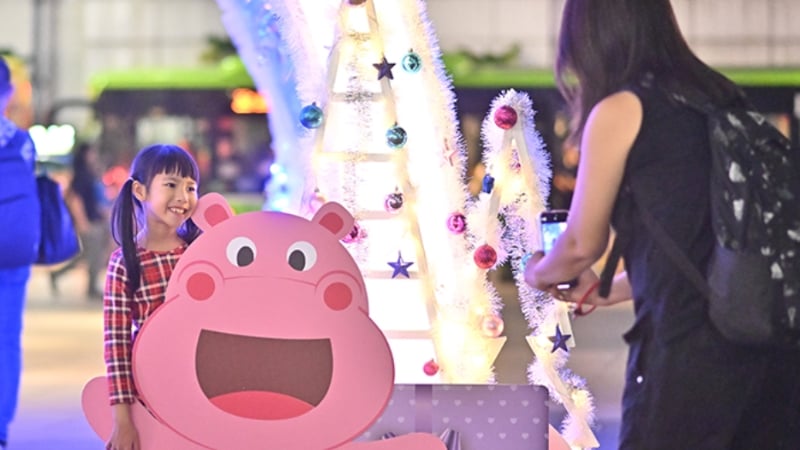 a child posing with a standee at the orchard road christmas market