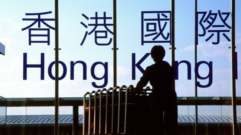 silhouette of a woman pushing luggage carts in hong kong