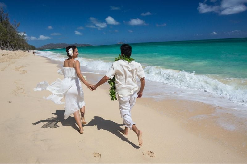 Newlyweds run along Waimanalo Beach, Waimanalo, Oahu, Hawaii